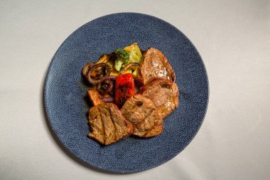 Restoranda servis edilen ızgara biftek ve ızgara sebze.