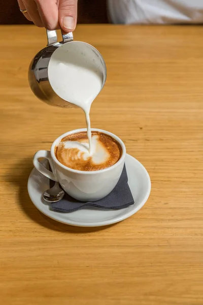Cappuccino maken, melk in koffie gieten — Stockfoto