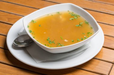 Beyaz tabakta servis edilen basit bir tavuk çorbası.