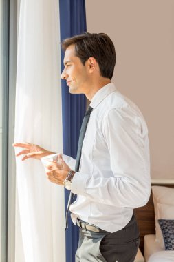 Yakışıklı genç işadamı otelin önünde kahve içiyor.