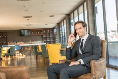 Yakışıklı genç işadamı otel C 'de cep telefonuyla konuşuyor.
