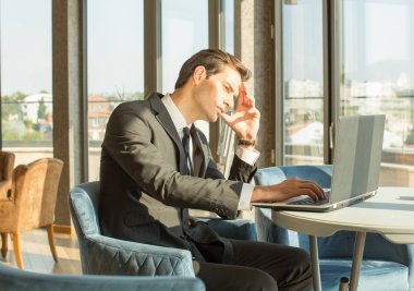 Otel kafesinde defter üzerinde çalışan yakışıklı genç bir işadamı.