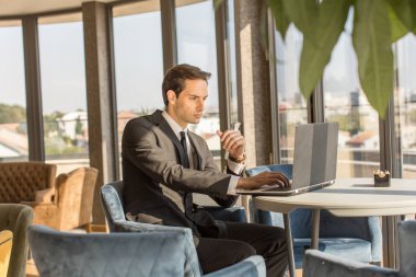 Otel kafesinde defter üzerinde çalışan yakışıklı genç bir işadamı.