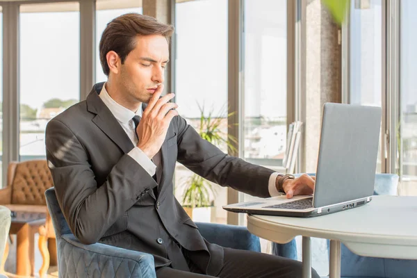 Knappe jonge zakenman werkt aan zijn notitieboekje in hotel cafe — Stockfoto