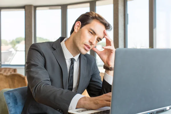 Knappe jonge zakenman werkt aan zijn notitieboekje in hotel cafe — Stockfoto