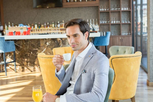 Guapo joven hombre de negocios bebe café en la cafetería del hotel — Foto de Stock