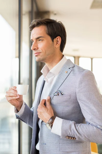 Όμορφος νεαρός επιχειρηματίας πίνει καφέ μπροστά από το ξενοδοχείο — Φωτογραφία Αρχείου