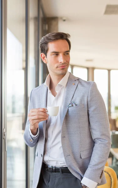 Guapo joven hombre de negocios bebe café en frente del hotel w — Foto de Stock