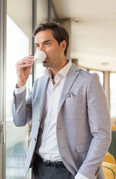 Όμορφος νεαρός επιχειρηματίας πίνει καφέ μπροστά από το ξενοδοχείο — Φωτογραφία Αρχείου
