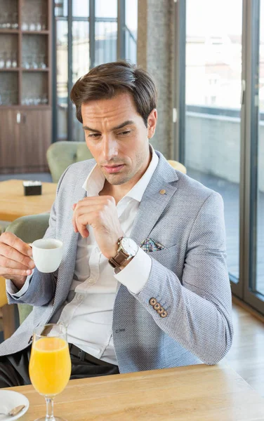 Όμορφος νεαρός επιχειρηματίας πίνει καφέ στο καφέ του ξενοδοχείου — Φωτογραφία Αρχείου