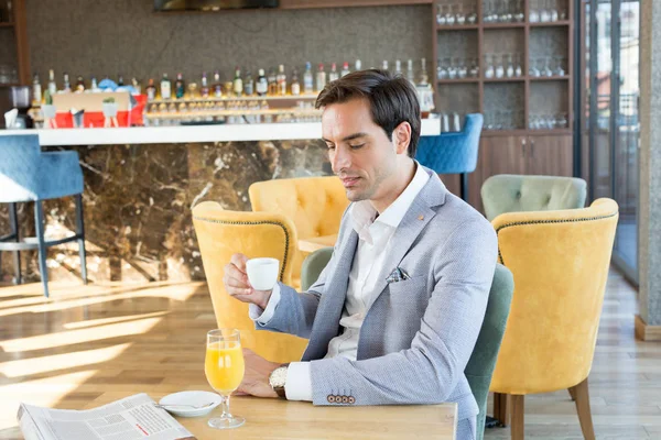 Guapo joven hombre de negocios bebe café en la cafetería del hotel —  Fotos de Stock