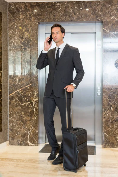 Guapo joven hombre de negocios hablando en el teléfono celular en el hotel lo —  Fotos de Stock