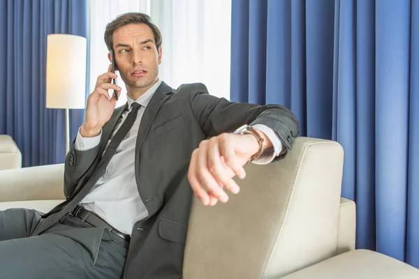 Biznesmen rozmawiający przez telefon komórkowy w swoim pokoju hotelowym — Zdjęcie stockowe