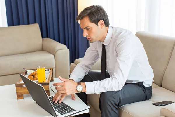 Красивый молодой бизнесмен, работающий над ноутбуком в отеле — стоковое фото