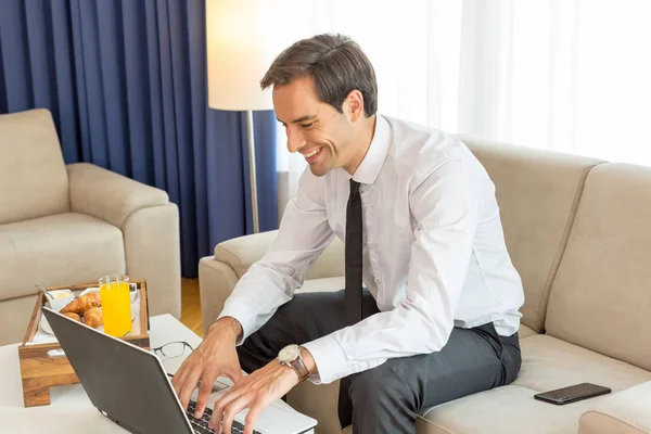 Gelukkig knap jong zakenman werken op de notebook in een ho — Stockfoto