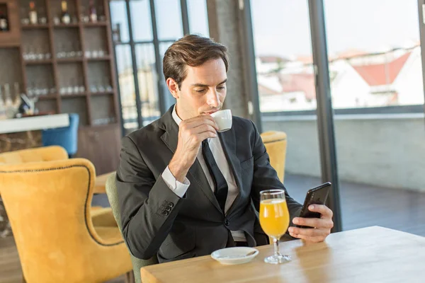 Όμορφος νεαρός επιχειρηματίας που χρησιμοποιεί το κινητό του στο καφέ του ξενοδοχείου — Φωτογραφία Αρχείου