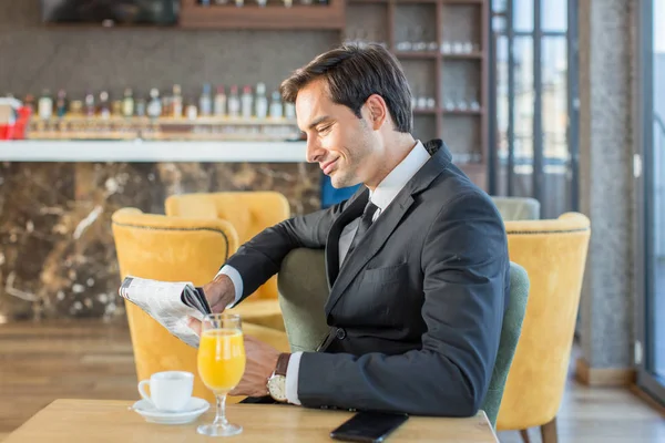 Όμορφος νεαρός επιχειρηματίας διαβάζει εφημερίδα στο καφέ του ξενοδοχείου — Φωτογραφία Αρχείου