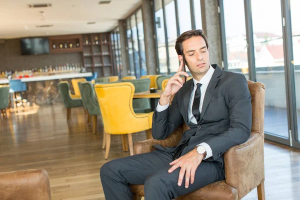 Guapo joven hombre de negocios hablando por el teléfono celular en el hotel c —  Fotos de Stock