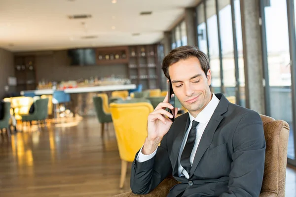 一个年轻英俊的生意人在酒店里用手机聊天 — 图库照片