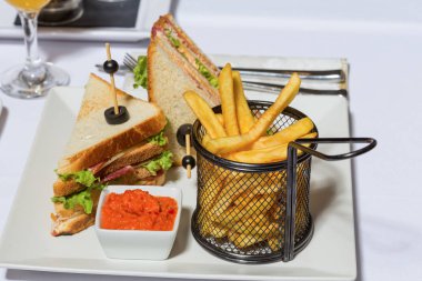 Restoranda beyaz tabakta servis edilen kulüp sandviçi.