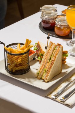 Restoranda beyaz tabakta servis edilen kulüp sandviçi.