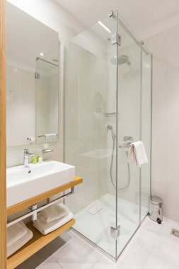 İçinde cam duş kabini olan lüks bir otel banyosu.
