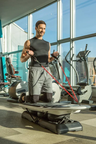 Bonito homem exercitando na máquina de ginásio de prancha — Fotografia de Stock