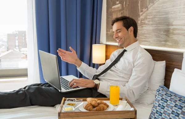 Szczęśliwy biznesmen w garniturze pracujący na łóżku hotelowym na jego kompozycji — Zdjęcie stockowe