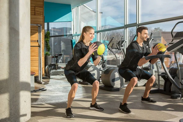 Man and woman doing electro muscular stimulation training in a m