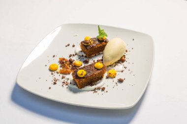 Beyaz tabakta servis edilen tatlı, vanilyalı dondurmalı çiğ kek.