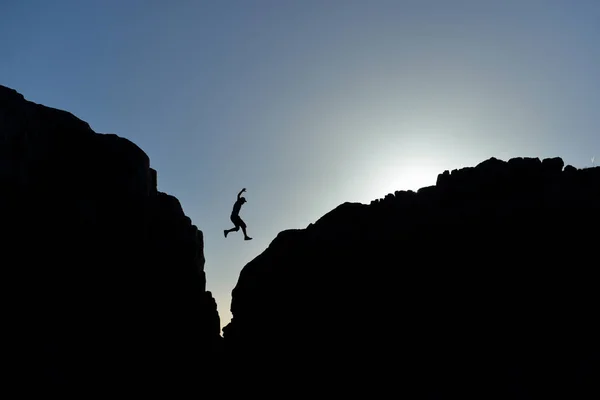 Muž, který skočil na skalách v silueta — Stock fotografie