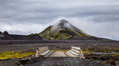 Wooden bridge in Iceland on hill background with cloudy sky clipart