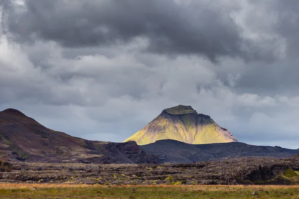Vista su una montagna enorme e piccola casa in Islanda con cielo drammatico — Foto Stock