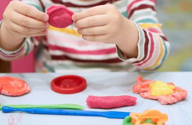 Covid-19 karantinası sırasında renkli plastikinle oynayan çocuk elleri