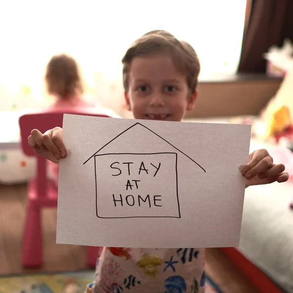 Παιδί που δείχνει χάρτινες λέξεις μένει σπίτι κατά τη διάρκεια μιας επιδημίας του κορωναϊού. Covid-19. — Φωτογραφία Αρχείου