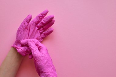 Pembe arka planda pembe eldivenli eller. Coronavirus covid-19 virüs önleme konsepti. Pembe arka plan, kopyalama. Düzen, üst görünüm, düzlük.