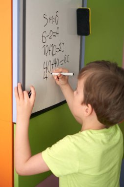 Evde online matematik dersi sırasında ev ödevi, Covid-19 karantinasında sosyal mesafe, online eğitim konsepti, evde eğitim. Çocuk evde, anaokulu kapalı. 6 yaşında çocuk, beyaz tahta..