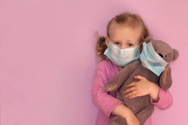 Yüz maskeli oyuncak ayılı kız. Beyaz çocuk Coronavirus Covid-19 salgını sırasında yüz maskesi takıyor. Evde kal, sosyal mesafeyi koru, kendini izole et. karantina sırasında.
