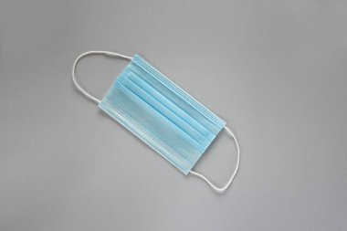 Coronavirus önleme maskesi. Sosyal mesafe, Covid-19 karantinası sırasında kendini izole etme. Güvenli nefes alma maskesi düzeni, üst görünüm, düz alan, gri arkaplan.