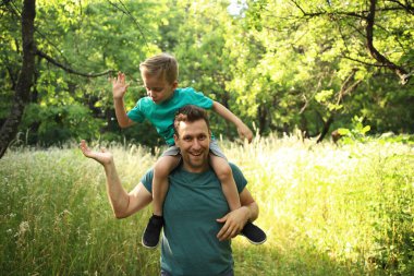 Mutlu baba ve oğul oynaşmaları ve sarılmaları. Aile yürüyüşü. Birlikte yaz zamanı, güneş ışığı. Babalar günün kutlu olsun..