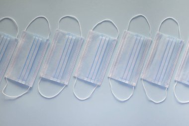 Coronavirus önleme maskesi. Sosyal mesafe, Covid-19 karantinası sırasında kendini izole etme. Güvenli nefes alma maskesi düzeni, üst görünüm, düz yatış, mavi arkaplan.