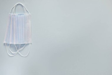 Coronavirus önleme maskesi. Sosyal mesafe, Covid-19 karantinası sırasında kendini izole etme. Güvenli nefes alma maskesi düzeni, üst görünüm, düz yatış, mavi arkaplan.
