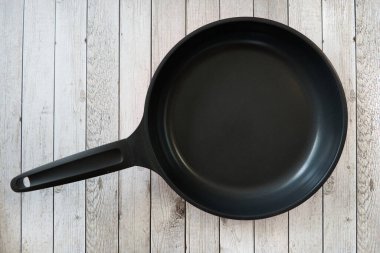 Mutfak masasındaki boş tava. Ahşap mutfak arka planındaki mutfak masasındaki boş tava. Üst görünüm.