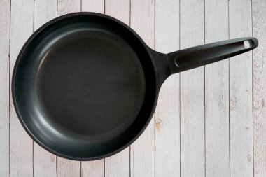 Mutfak masasındaki boş tava. Ahşap mutfak arka planındaki mutfak masasındaki boş tava. Üst görünüm.