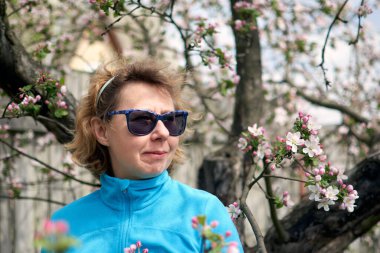 Bahar çiçeği ağacında gülümseyen orta yaşlı sakin bir kadın. Huzurlu, düşünceli, olgun, yaşlı, yaşlı ve sakin bir büyükanne. İyi eğlenceler..