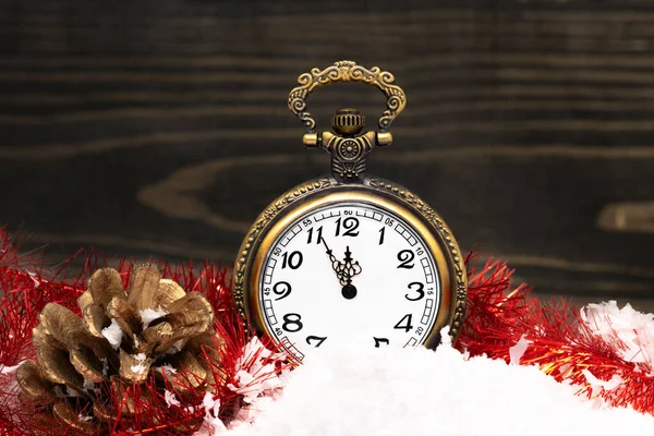 New Year clock. Decorated with gold cone on snow.