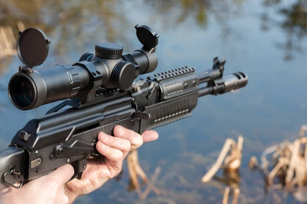 A man is holding a rifle magazine camouflage clothes