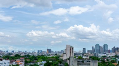 Büyük şehrin üstündeki güneşli bir günde canlı mavi gökyüzünde güzel, tüylü bir bulut oluşumu, çatıdan manzara. 