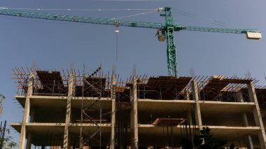 Yüksek kule Crane 'in yukarıdan görünüşü, hareket eden makine ve bina, en üst katta iskele, beyaz kabarık bulutların altında açık mavi gökyüzü