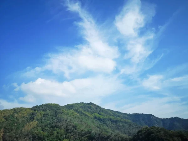 緑の山の上の晴れた日に鮮やかな青空に美しい白いふわふわの雲を上から見る — ストック写真